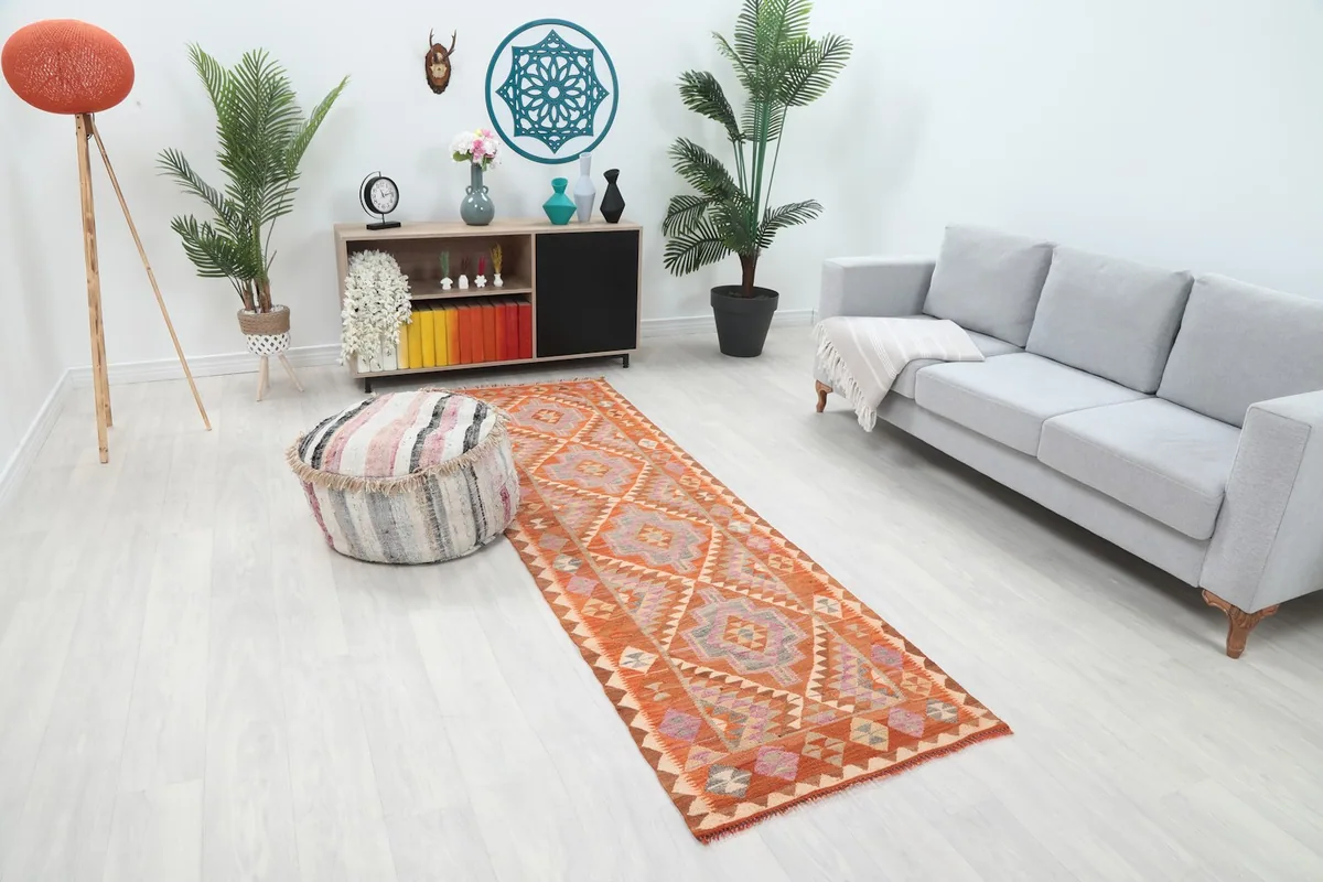 Long shot of the hand-knotted runner rug in a room, highlighting its vibrant orange and geometric design
