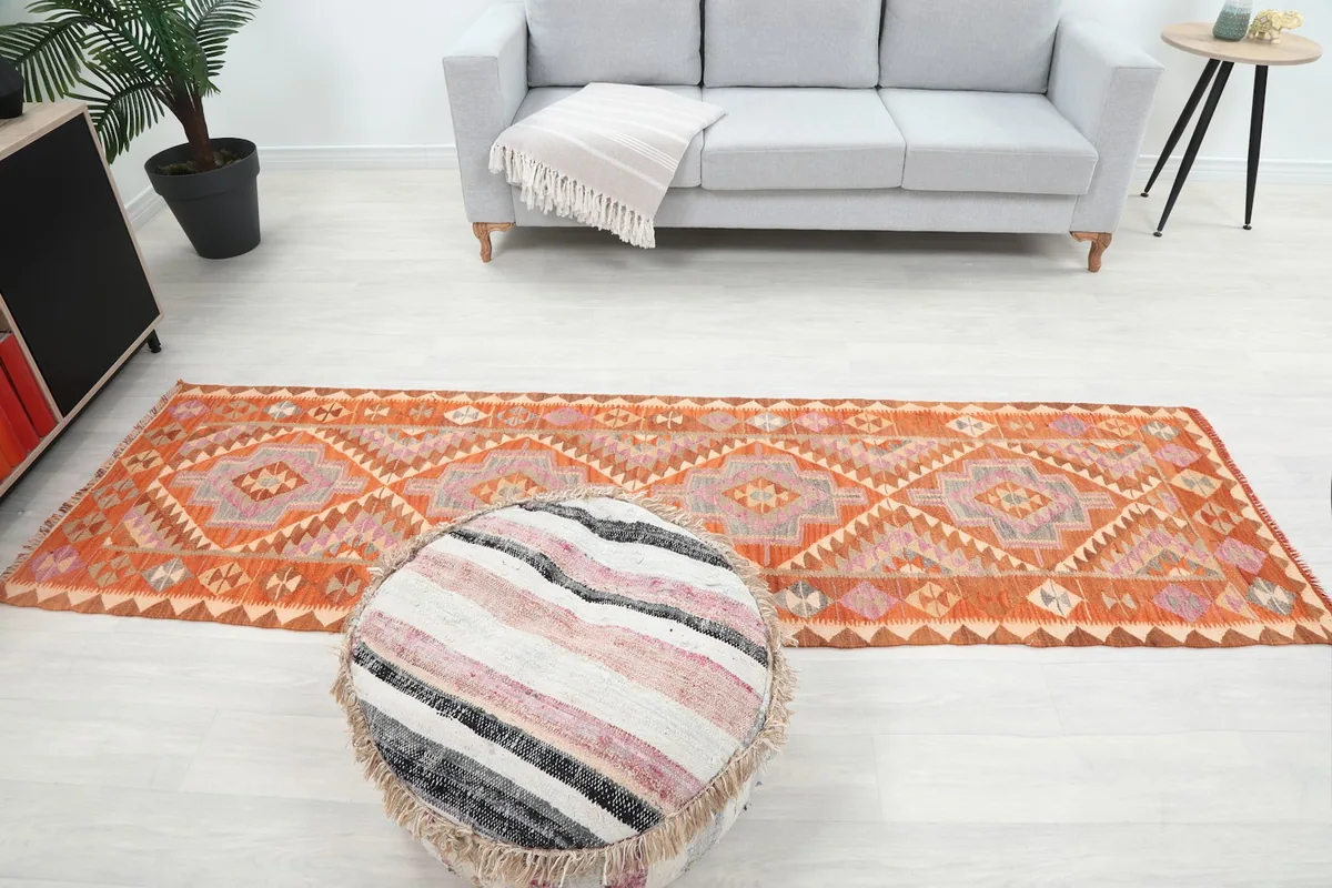 Full view of the runner rug from a higher angle in a room, showing its placement relative to a sofa and pouf