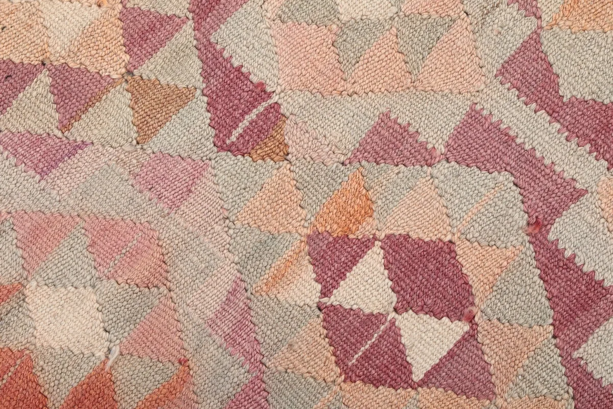 Texture close-up of the low wool pile, revealing individual knots and the distressed nature of the vintage rug.