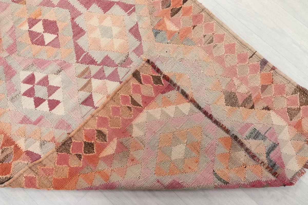 Folded corner of the rug revealing the hand-knotted construction from the back and the cotton foundation.