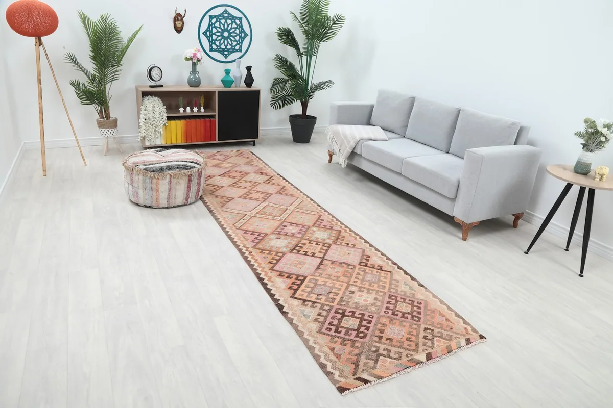 Long view of the rose and orange geometric runner rug extending through a living space with a sofa and ottoman.
