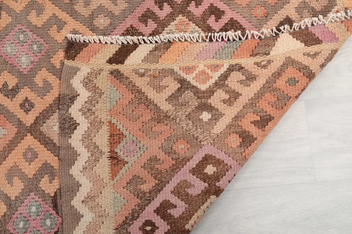 Close-up of the rug's edge, revealing the fringe and the tight weave of the wool pile and cotton foundation.