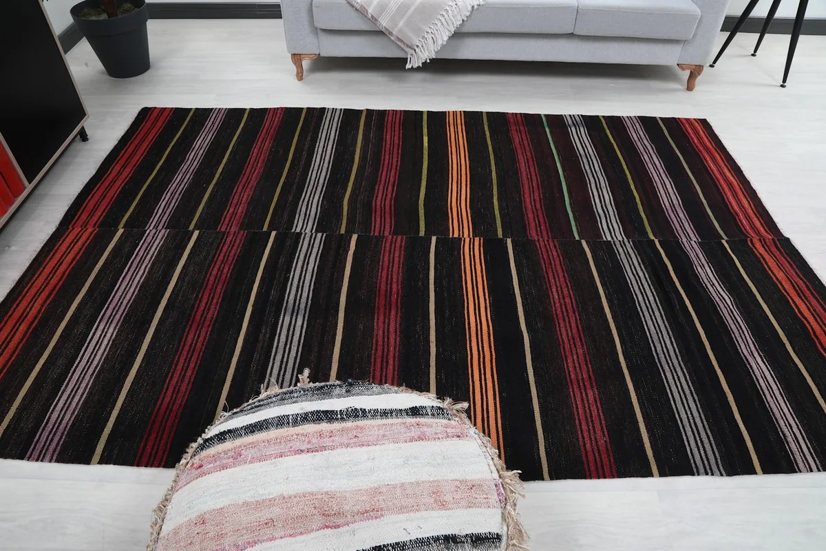 Full room view of the striped rug with a round ottoman in the foreground