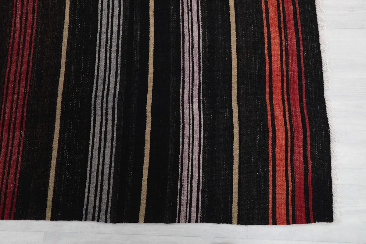 Detail of the rug's short end, highlighting the vertical stripes and black field