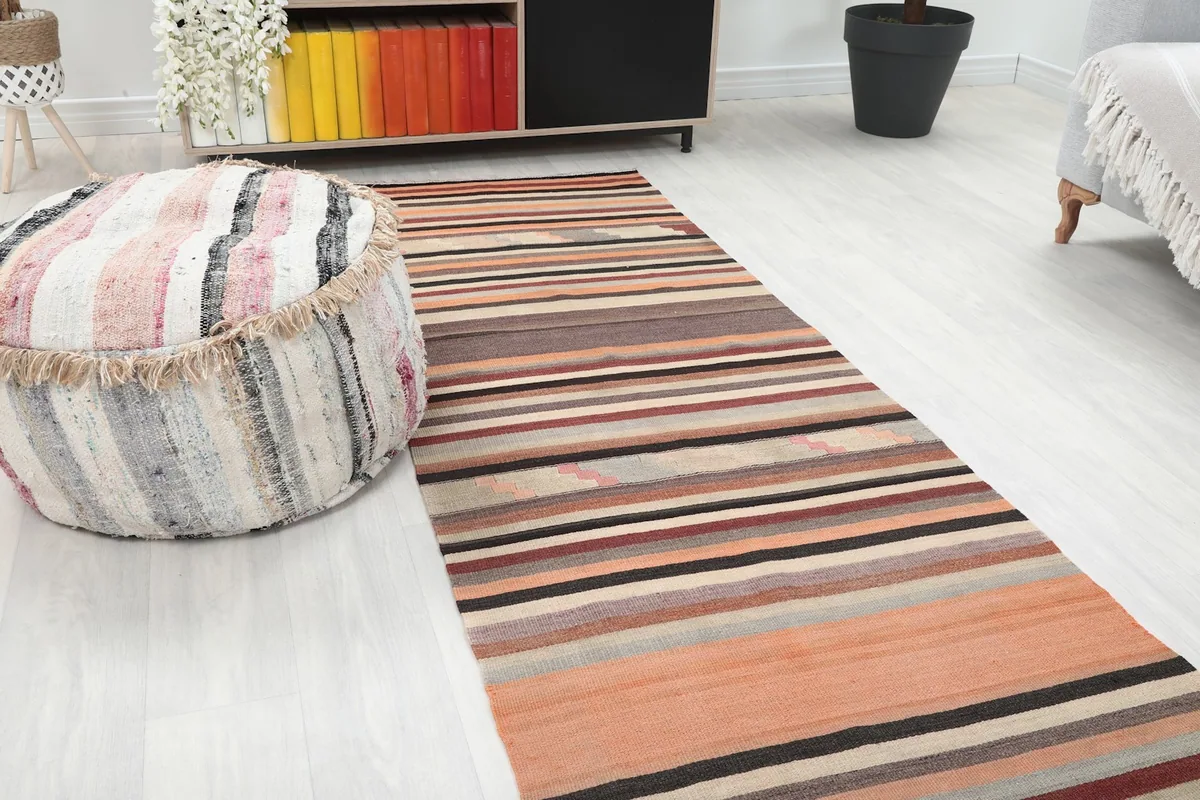 Close-up view of the striped Anatolian runner's texture and colors, with a decorative ottoman nearby.