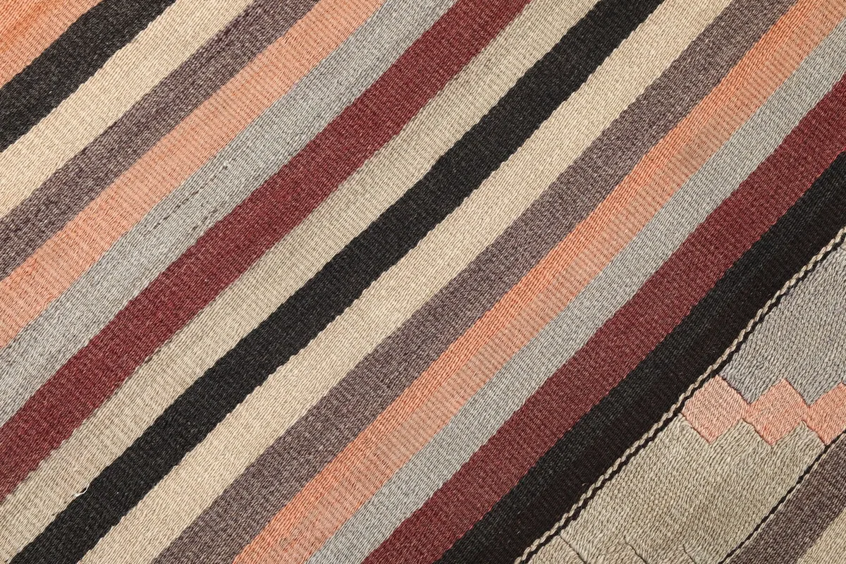 Diagonal view of the hand-knotted wool pile, showing the tight weave and color changes in the striped pattern.