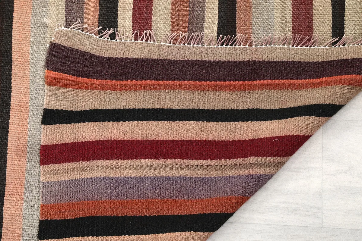 Close-up of the rug's underside, showing the hand-knotted cotton foundation and the consistent stripe pattern.