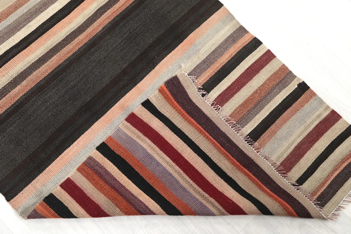 Corner of the runner folded back to reveal the back of the rug and the reverse side of the striped pattern.