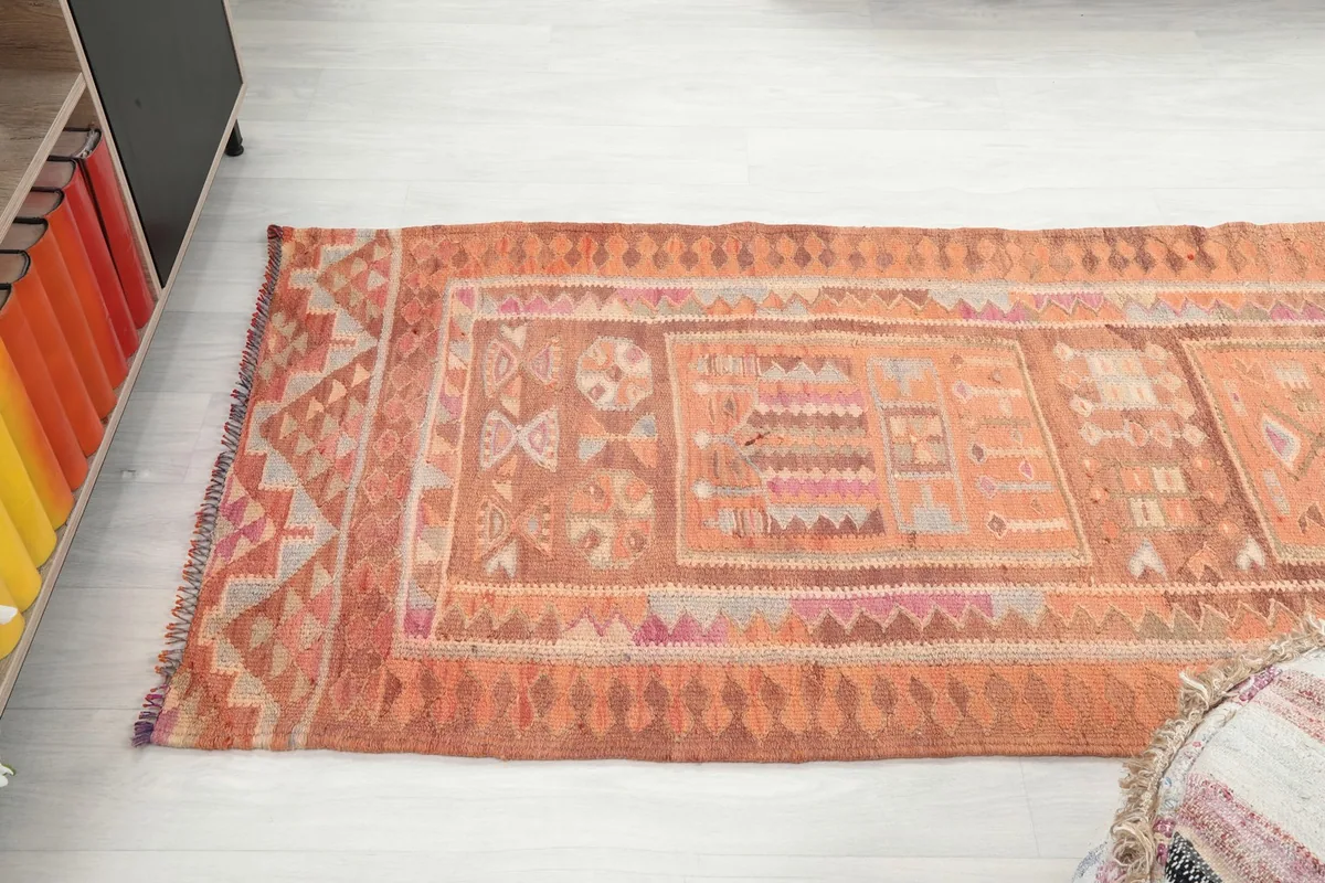 Angled perspective of the runner rug, emphasizing its length and the continuity of the rust and orange tribal design.