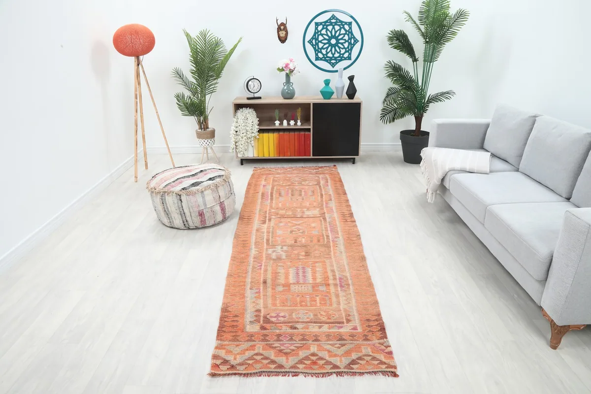 Vintage runner rug in an orange and rust palette, showcasing tribal geometric patterns in a modern room setting.