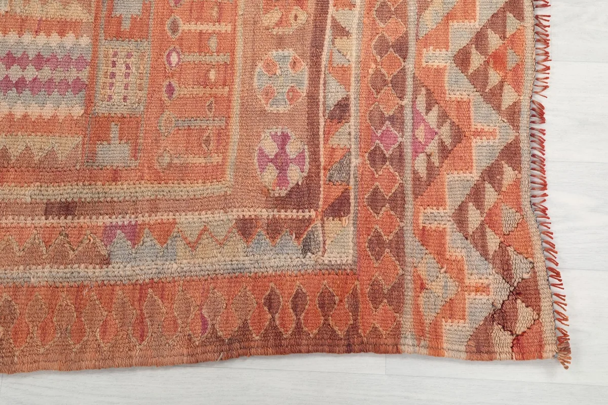Detailed view of the rug's border, showing intricate geometric patterns in rust, brown, and a touch of purple.