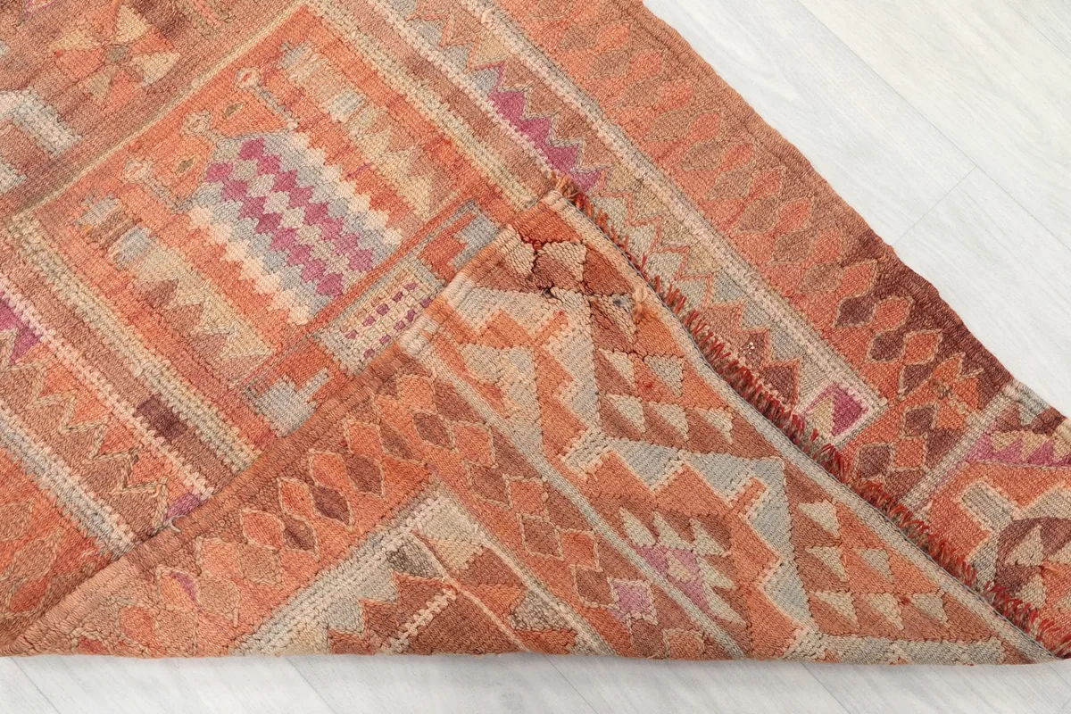 Folded corner of the hand-knotted rug, revealing the wool pile and cotton foundation, with clear geometric patterns.