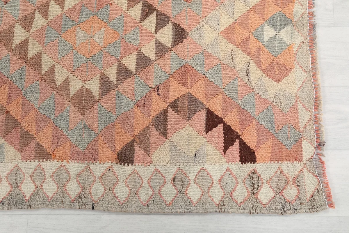 Detailed view of the rug's end, showing the geometric border and main field pattern with varied colors