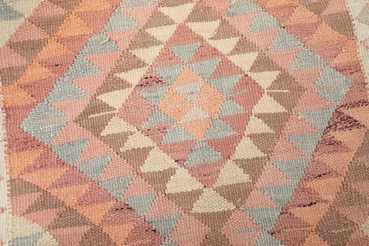 Tight detail shot highlighting the intricate hand-knotted weaving and color variations within the geometric pattern