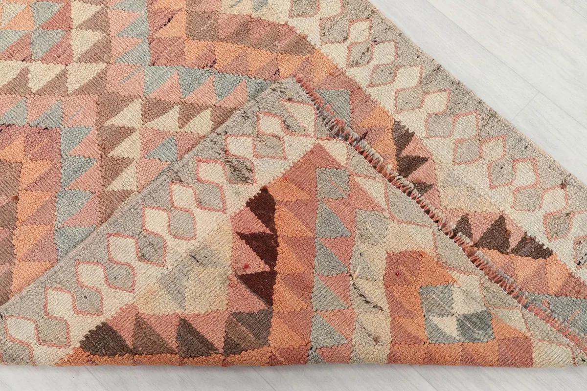 Folded corner of the rug revealing the backside of the hand-knotted wool pile and cotton foundation