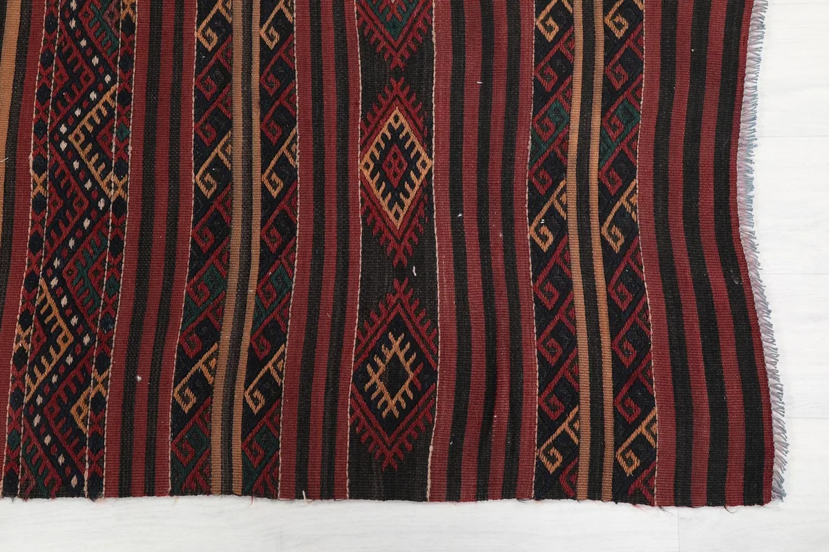 Detailed view of the hand-knotted geometric and tribal patterns in red, black, and gold