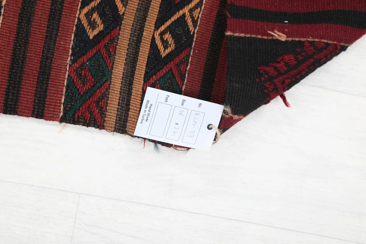 Corner of the rug with a tag showing size and material details, on a white floor