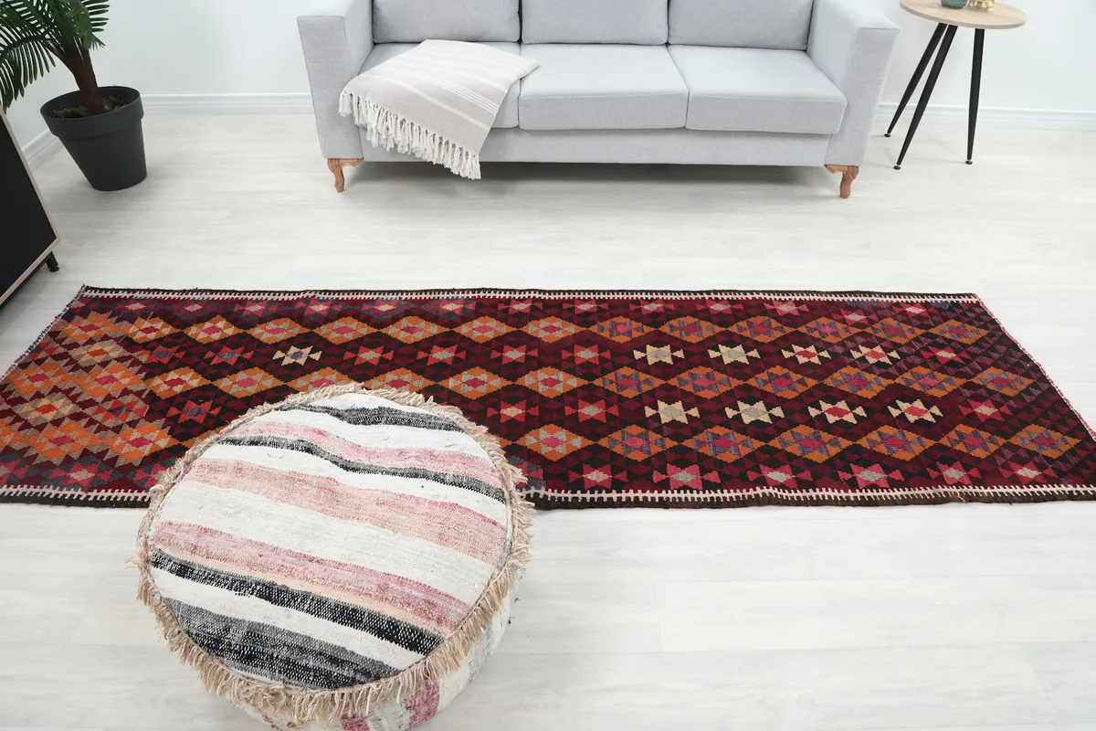Full length view of the red geometric runner rug in a living area with a sofa and ottoman.