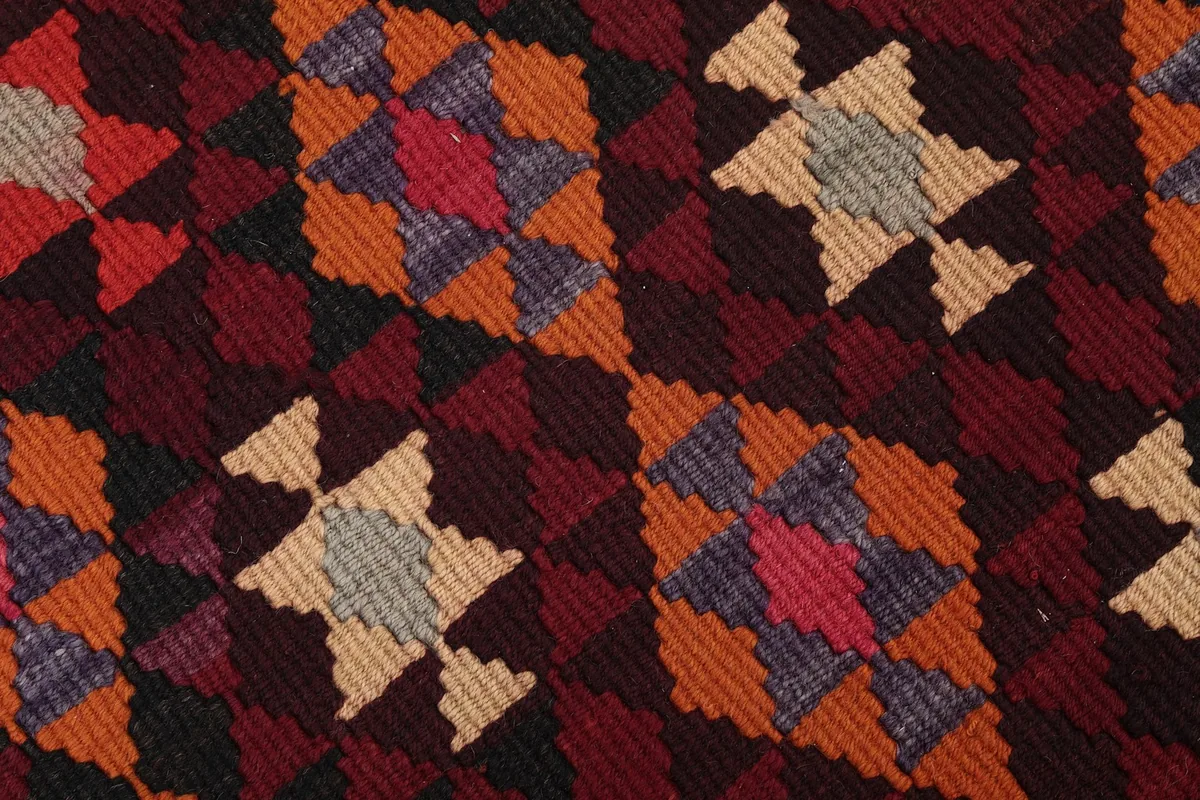 Close-up of the hand-knotted wool pile showing the texture and color variations in the geometric design.