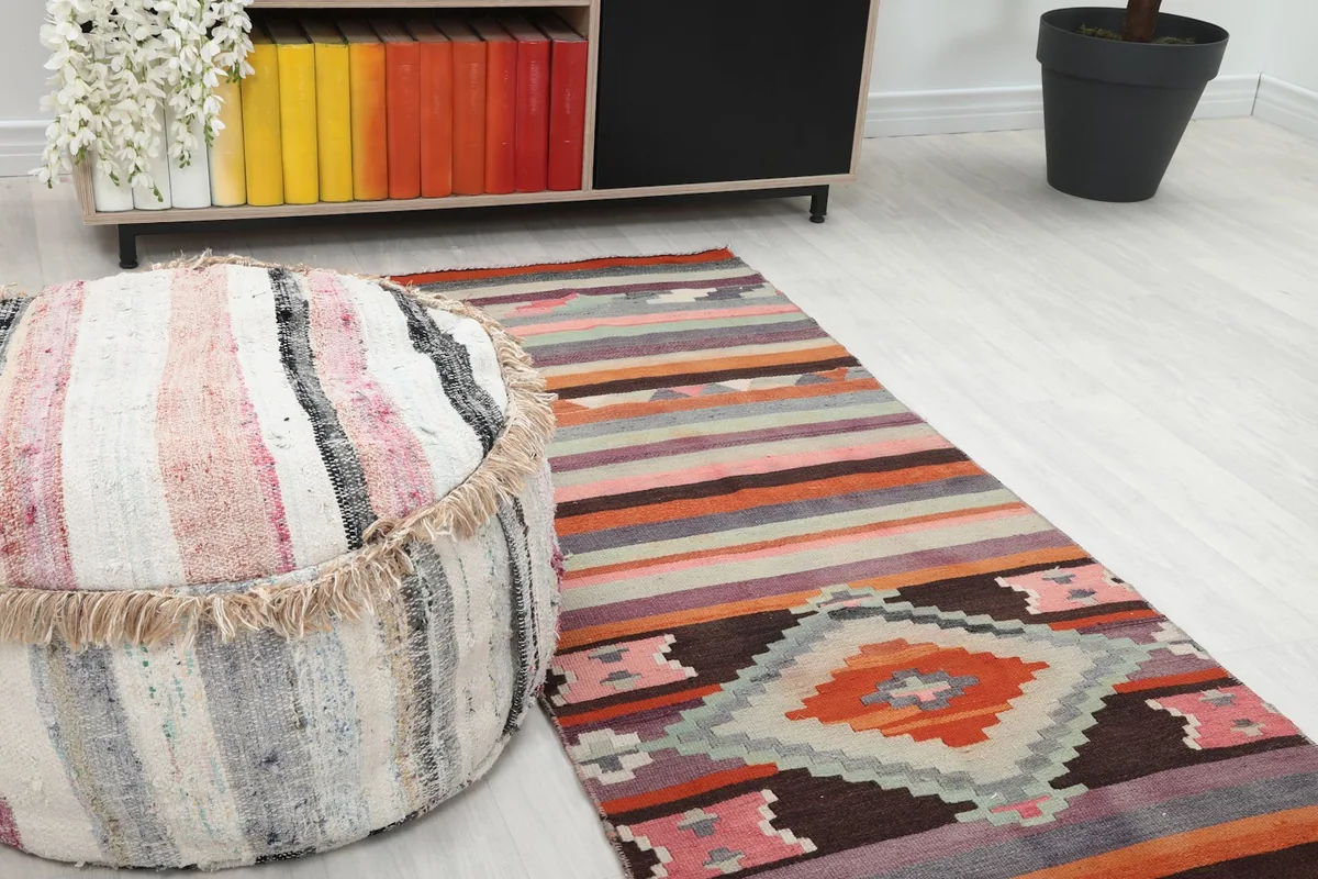 Close-up angle showing the central geometric diamond motif and striped patterns next to a decorative pouf.
