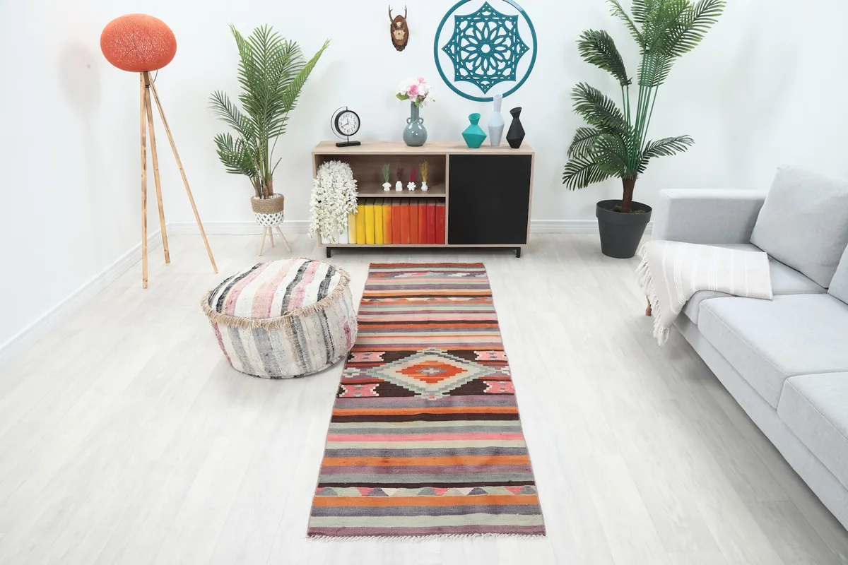 Multicolor geometric runner placed in a modern living room setting with a light sofa and plants.
