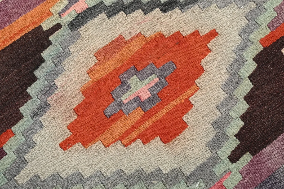 Extreme close-up of the hand-knotted wool pile, showing the texture and color variations within the central motif.