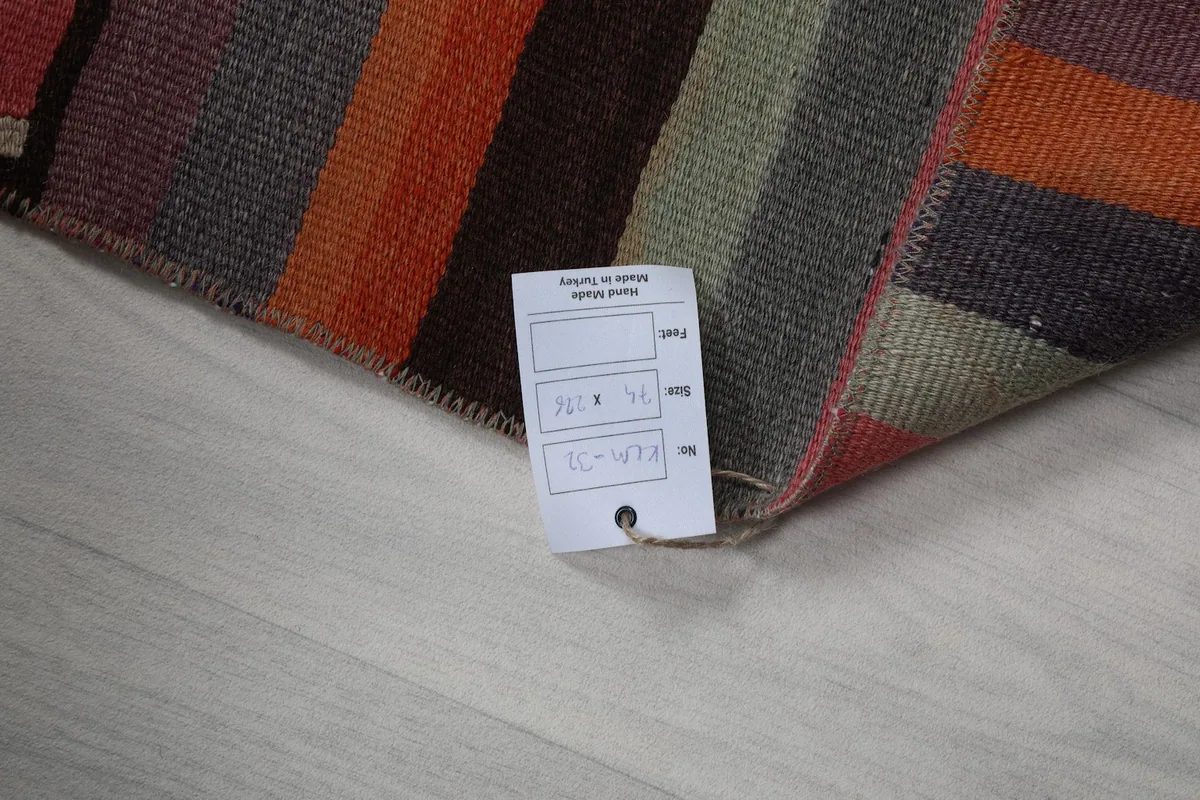 Corner of the rug with a tag indicating its dimensions and hand-knotted origin.