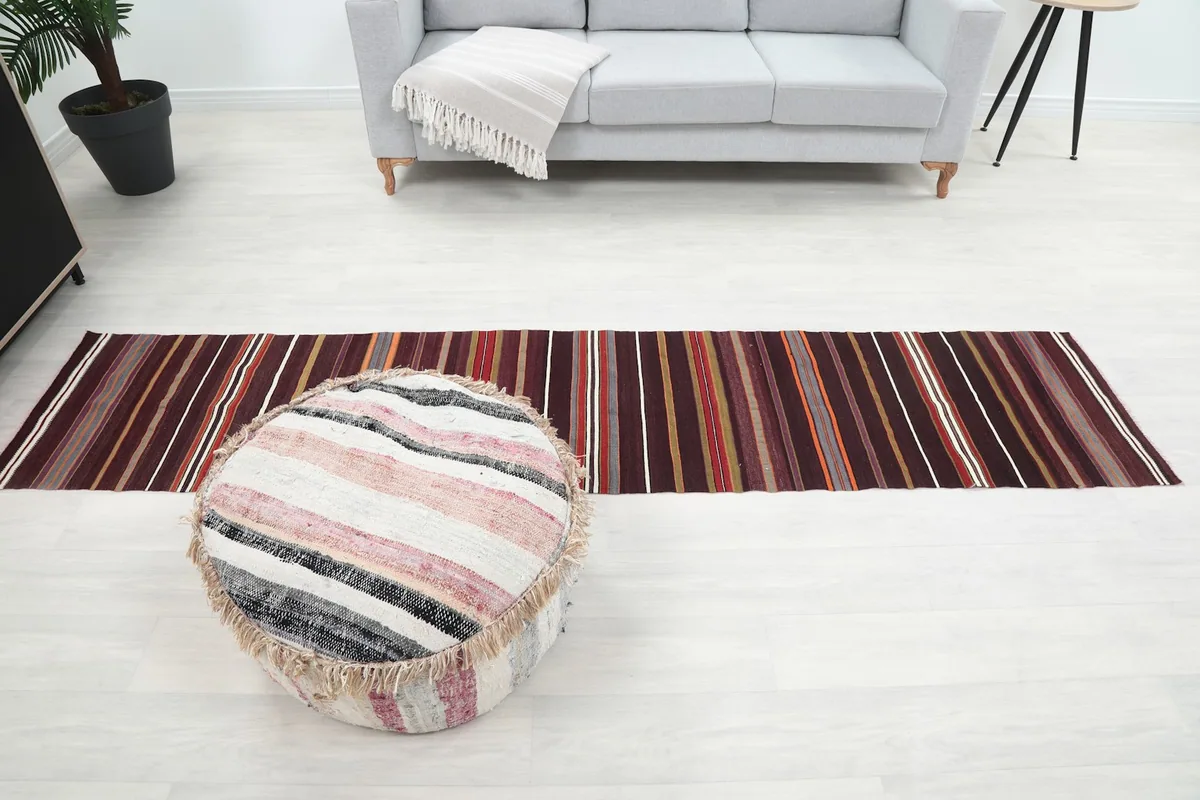 Long view of the runner rug in a room, extending towards a light gray sofa.