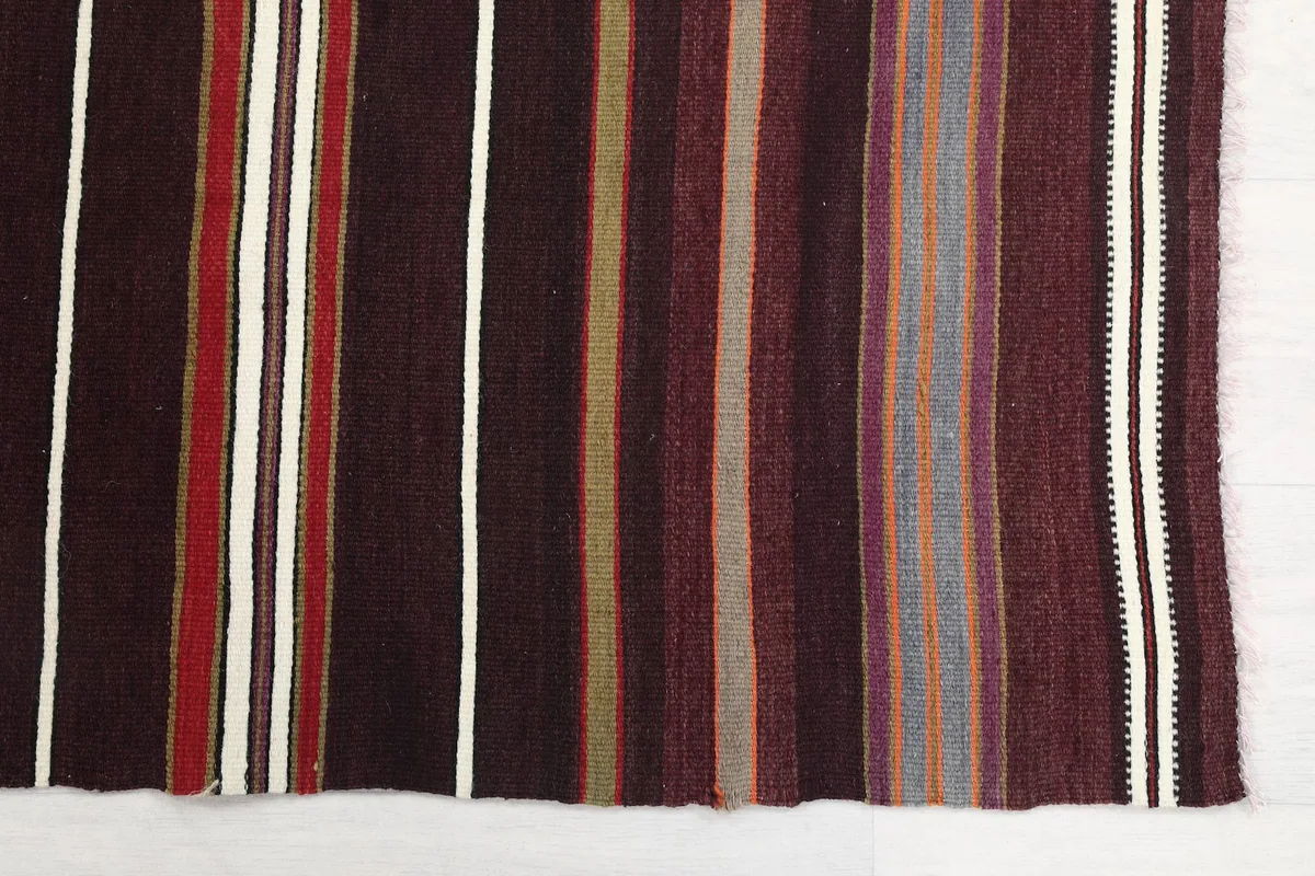 Close-up detail of the varied brown, red, gray, and ivory stripes on the vintage runner.