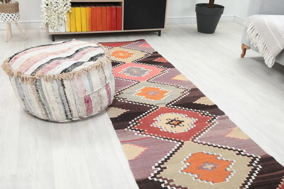 Close-up view of the runner in a room, showing its geometric design next to a textured ottoman
