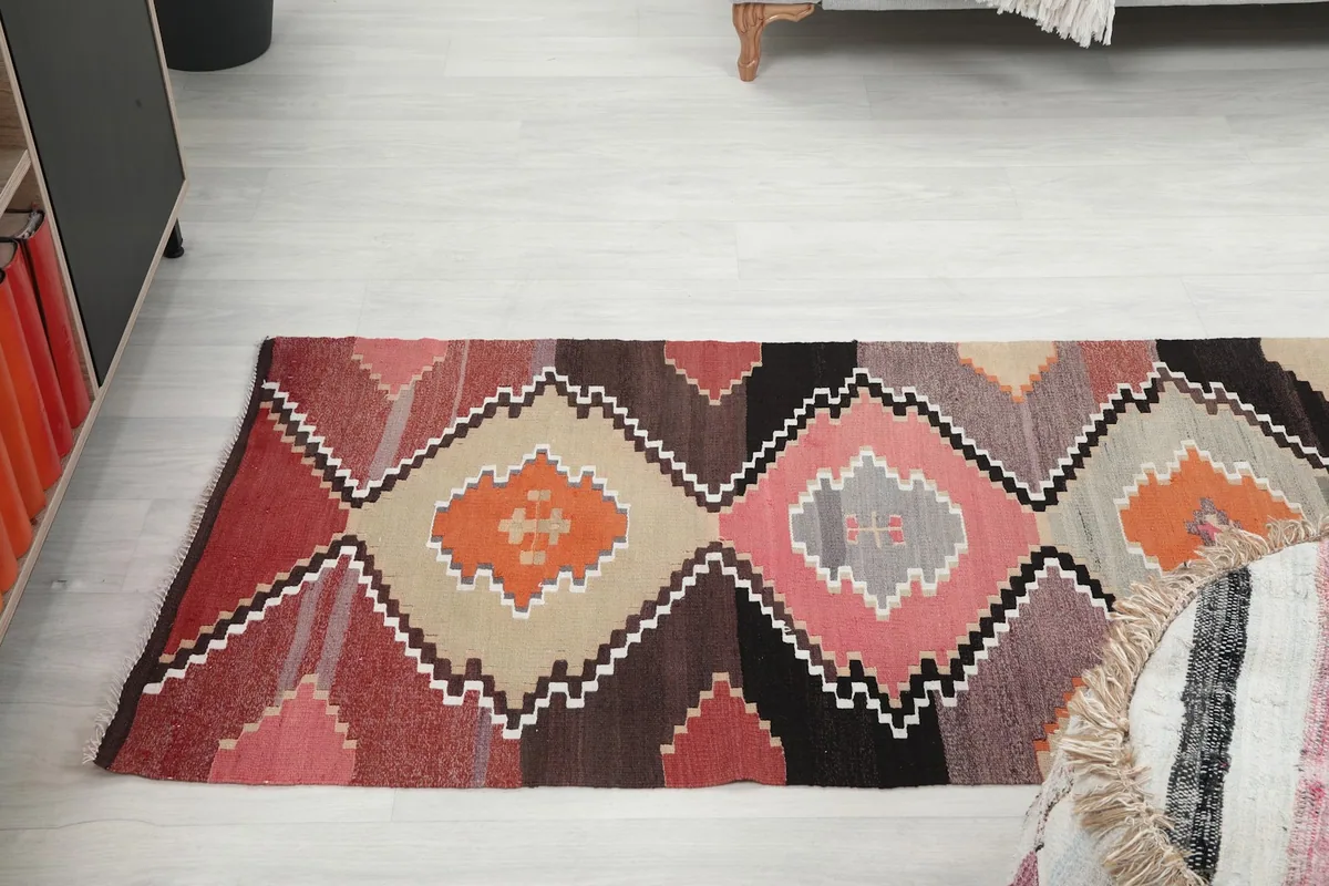 View of the runner rug laid out in a hallway, showing its scale relative to furniture.