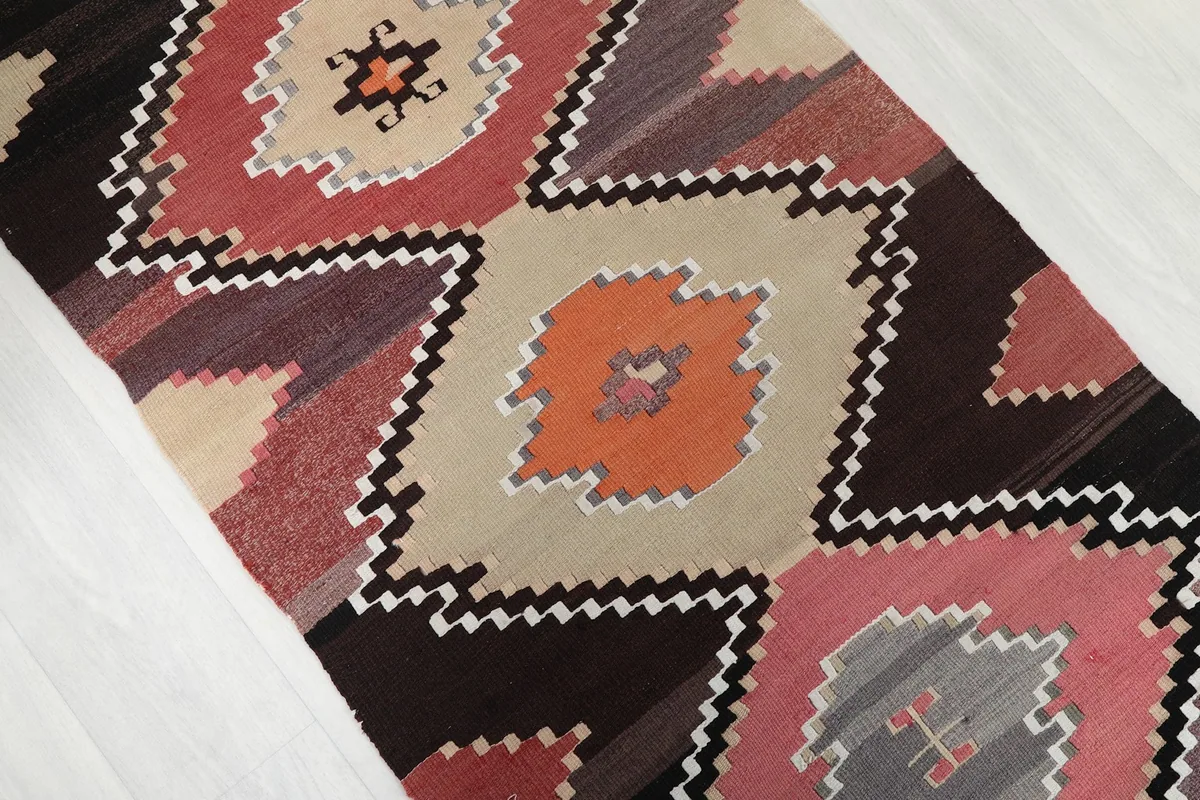 Close-up of the geometric diamond motifs in pink, orange, and beige with black and white outlines.
