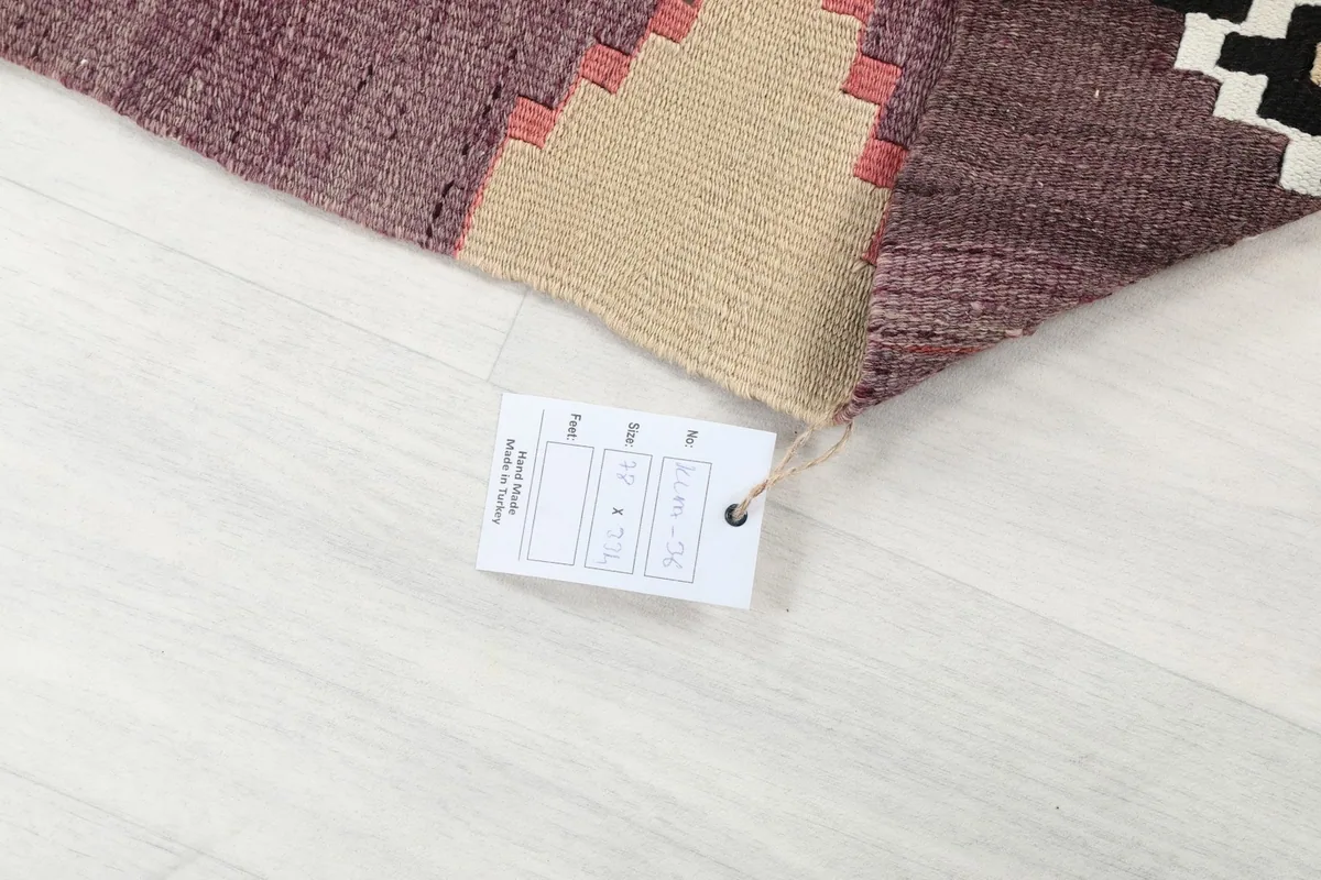 Rug corner with a product tag, indicating its vintage and hand-knotted origin.