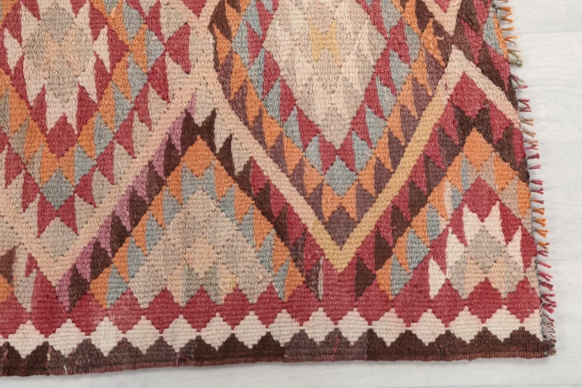 Detailed view of the intricate geometric diamond motifs and the blend of red, orange, and beige yarns