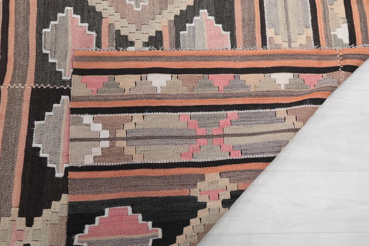 Corner of the rug folded back, showing the cotton foundation and reverse side of the weave
