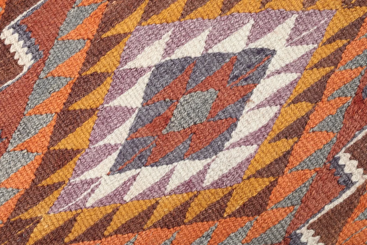Close-up of a central geometric diamond motif in purple, rust, gray, and ivory tones within the runner.