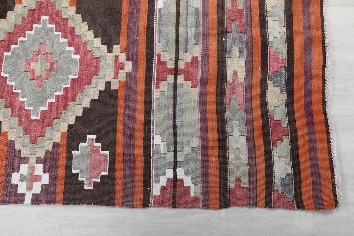 Close-up of the rug's edge, highlighting brown, rose, and orange stripes with geometric motifs