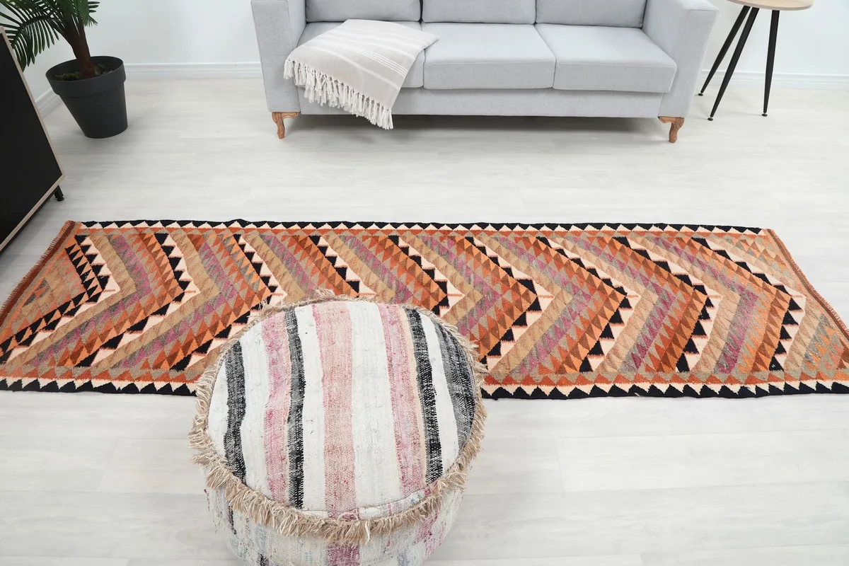 Full length view of the runner rug in a room with a sofa and ottoman