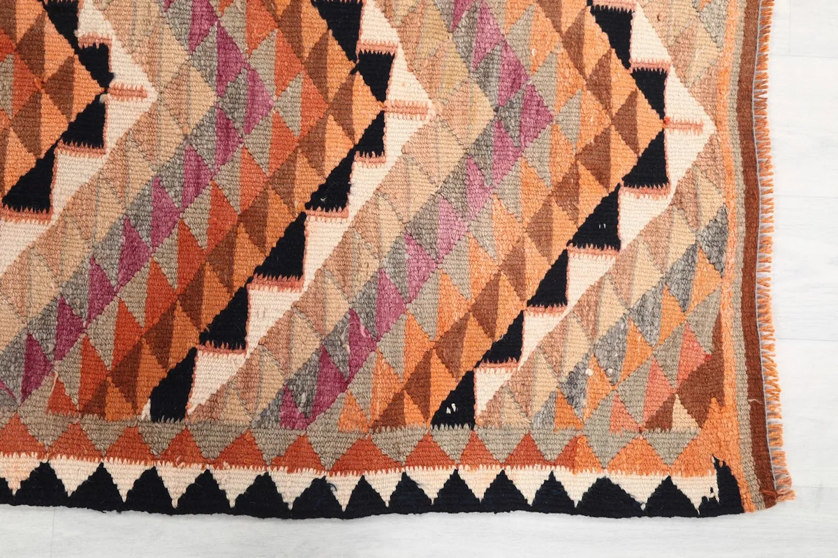 Detailed view of the geometric triangle pattern in shades of orange, black, beige, and rose