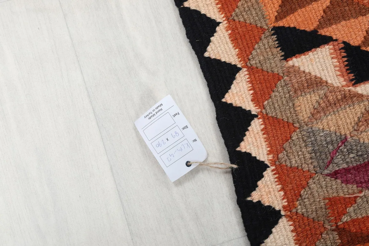 White tag with rug details, placed on the rug's surface to indicate size and origin