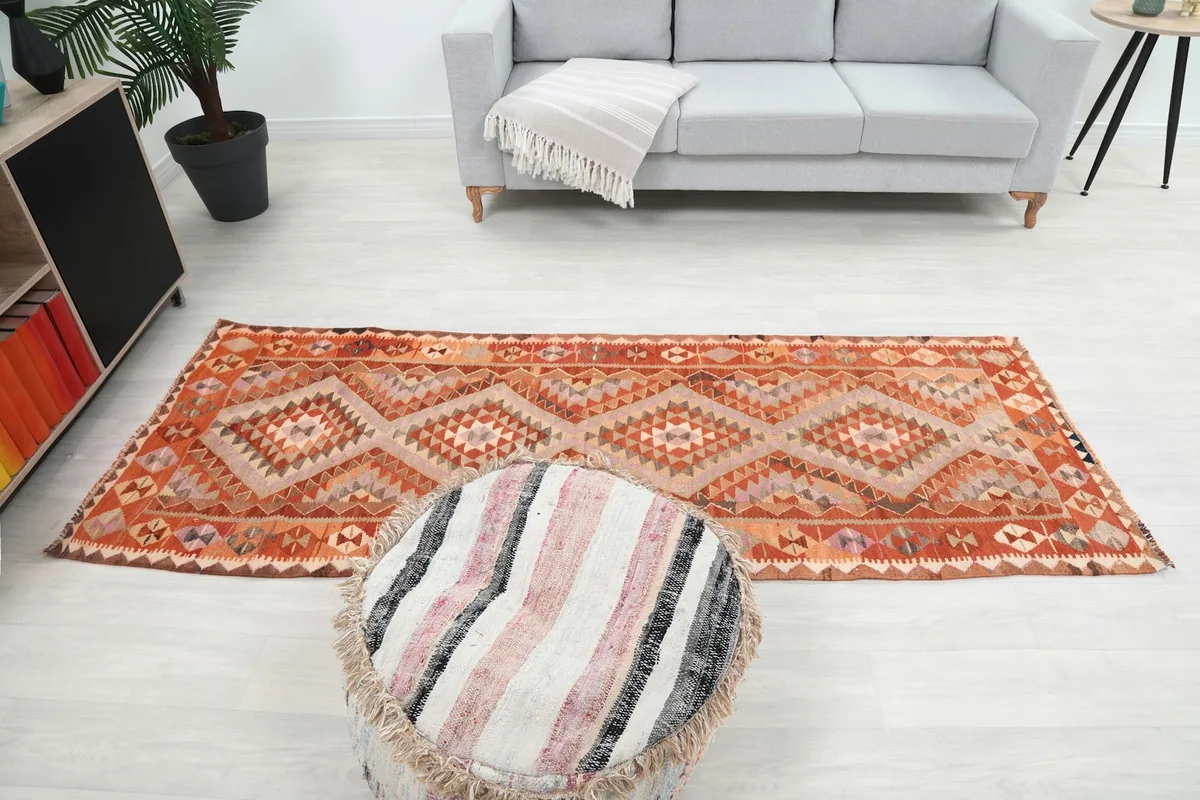 Full room view with the runner rug, sofa, and a striped pouf, showing its scale