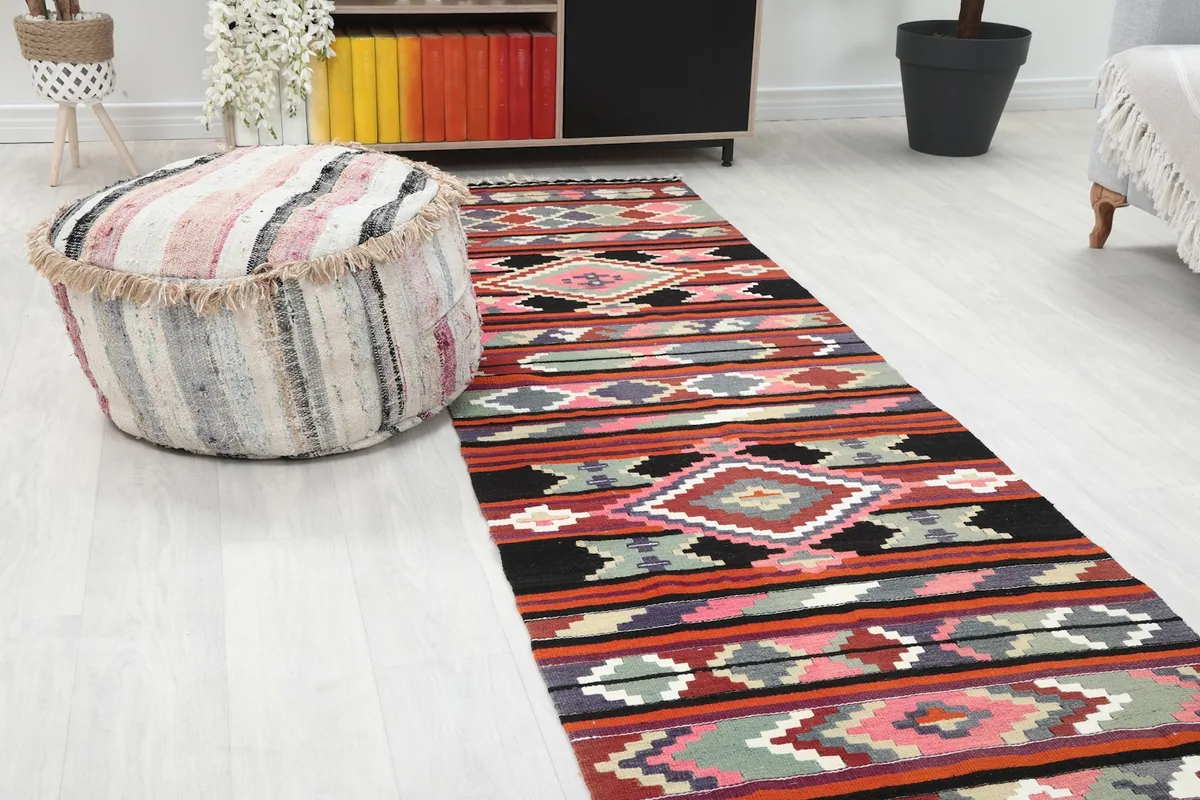 Close-up angled view of the runner's geometric patterns and colors, next to a striped ottoman.