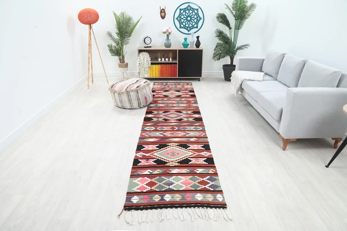 Vintage Anatolian runner with rust, pink, and black geometric patterns in a modern living room setting.