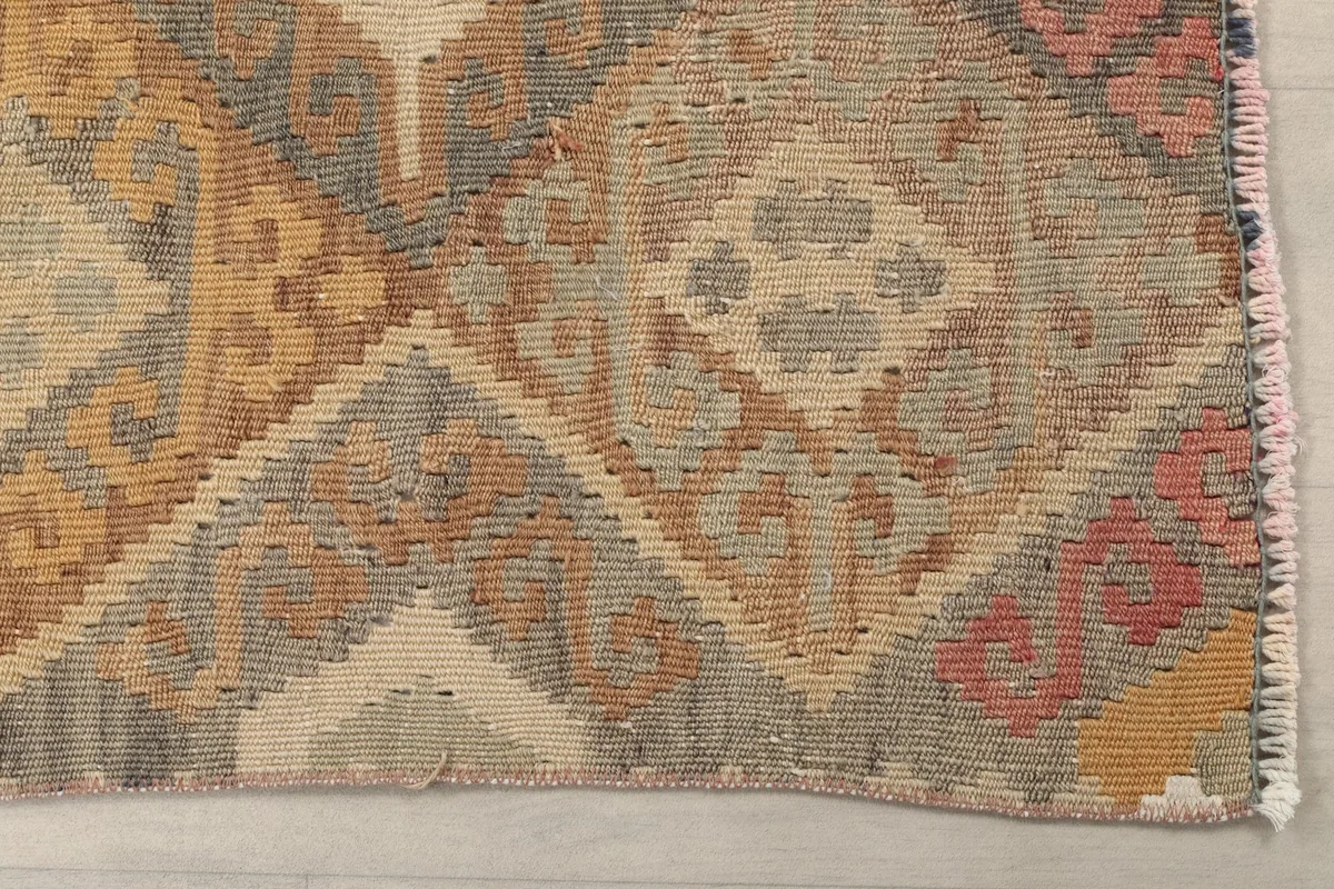 Detailed view of the geometric patterns in beige, gray, orange, and rose hues