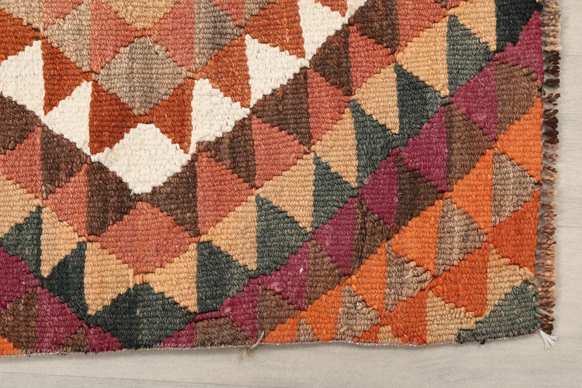 Detailed view of the rug's edge, showcasing the hand-knotted wool pile and various colored triangles.