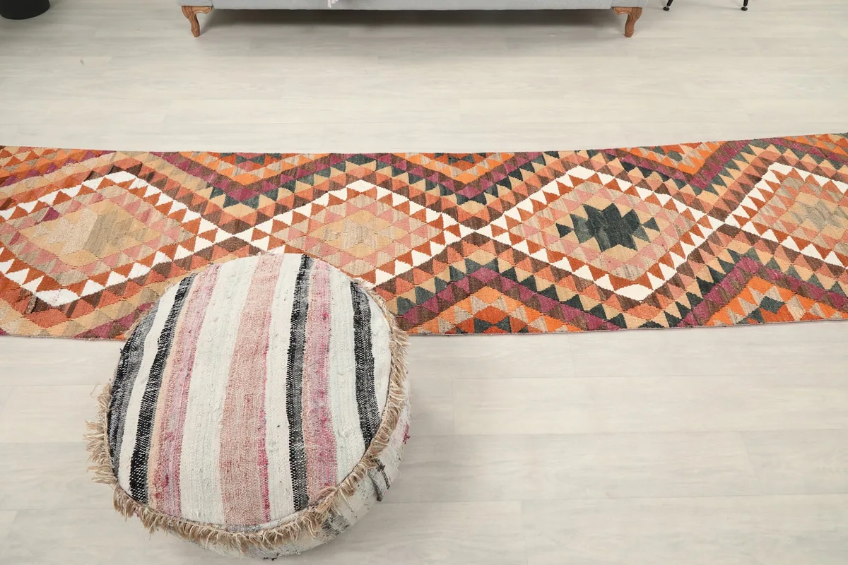 Full overhead view of the runner rug on a light floor, with a round pouf in the foreground.