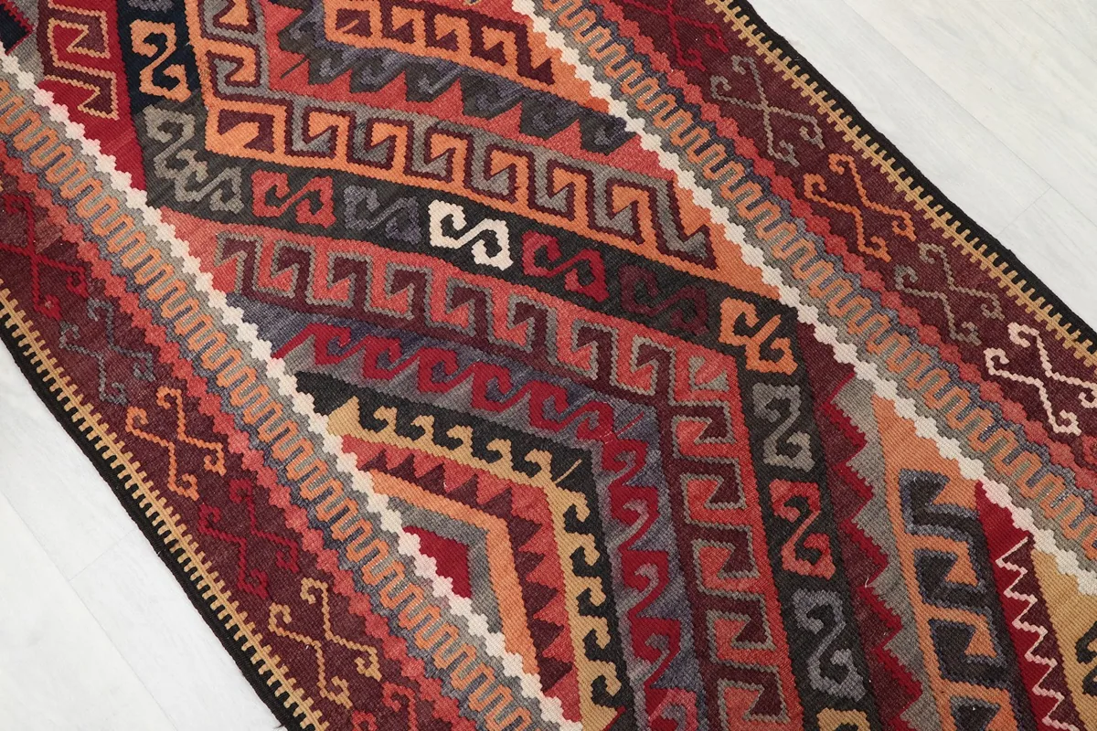 Close-up of the hand-knotted wool pile showing the varied red, black, and orange geometric shapes.