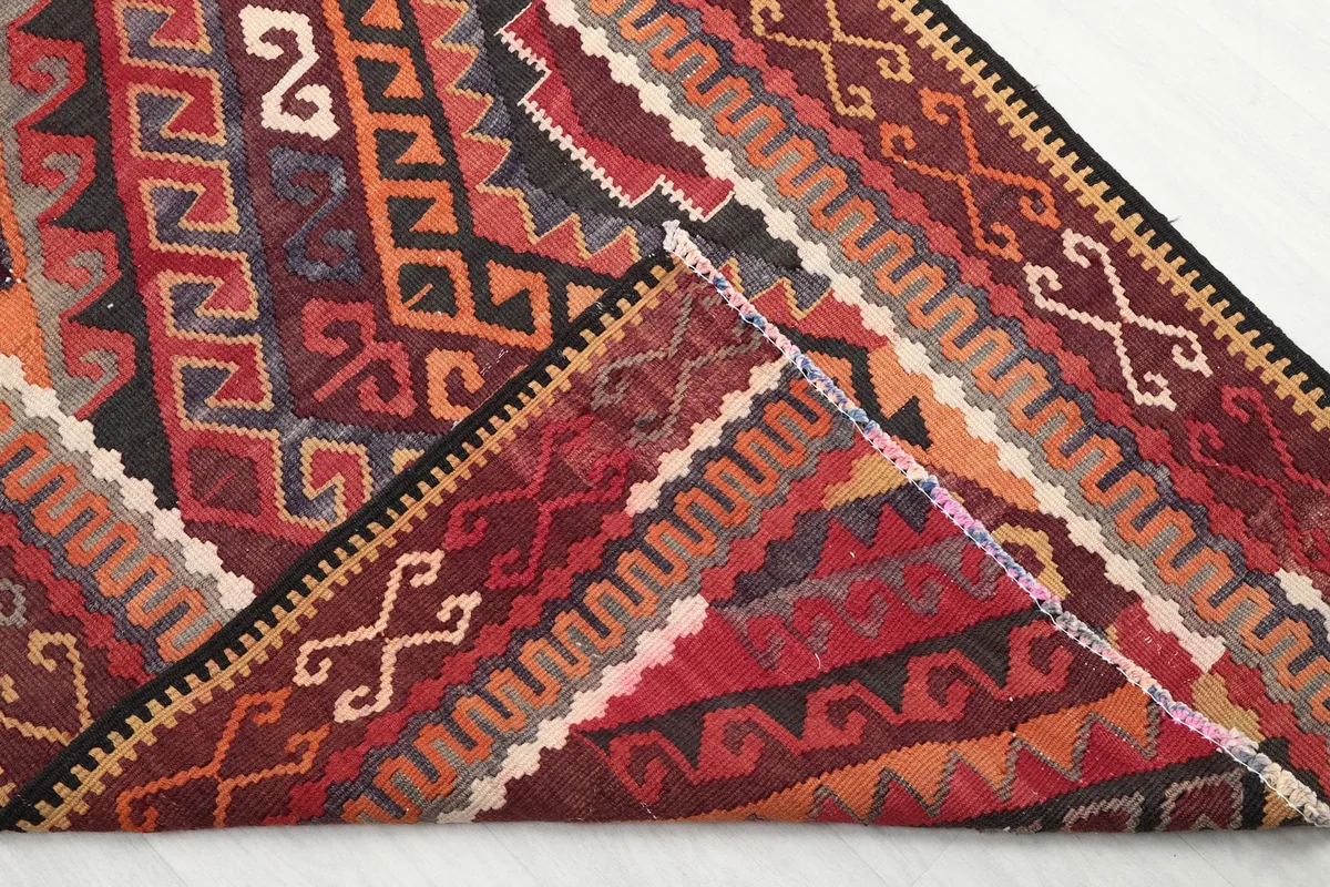 Corner of the runner rug folded to show the cotton foundation and the reverse side of the hand-knotting.