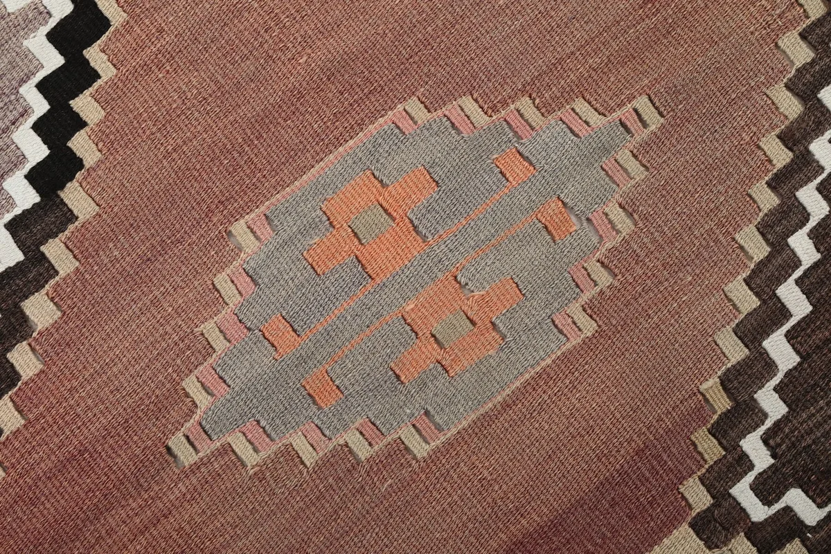 Detailed view of an orange and gray motif within a pink diamond section of the rug