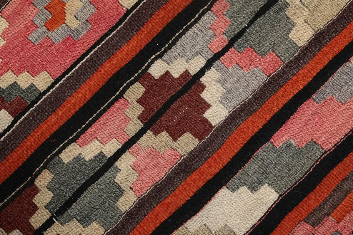 Close-up of the rug's wool pile showing various color blocks including red, gray, and orange